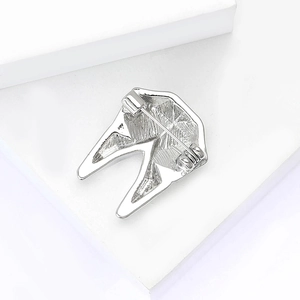 Macro shot of silver molar tooth brooch showing detailed texture and safety pin back