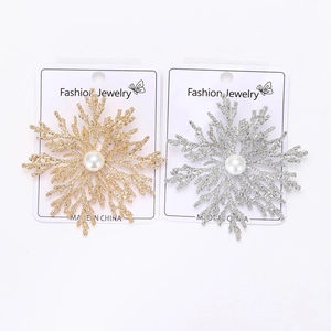 Detailed view of gold and silver snowflake brooches with white pearls on a display card