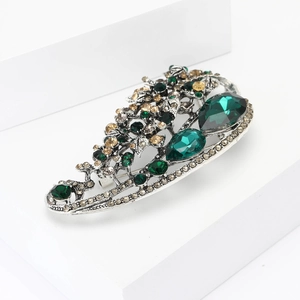 Detail of vintage silver brooch with emerald crystals and sparkling rhinestones
