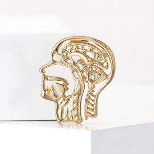 Unique gold anatomical brain brooch in side profile design on minimalist white steps