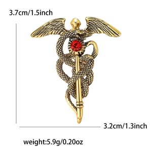 Broche caducée dorée vintage avec ailes d'ange et rubis rouge sur fond blanc classique