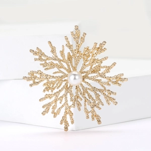 Elegant gold coral snowflake brooch with a central white pearl on a clean white display