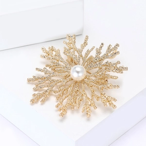 Elegant gold coral brooch with a large white pearl center on a white pedestal