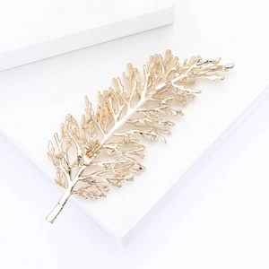 Detailed view of a gold leaf brooch with realistic textures on a white stone base