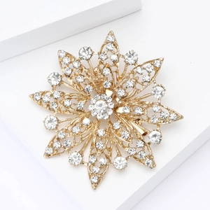Elegant gold hollow flower brooch with sparkling crystals on white geometric block