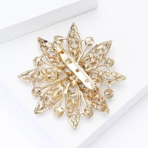 Detail view of the back of a golden snowflake brooch showing intricate hollow engraving