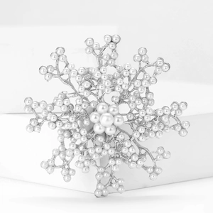 Elegant snowflake brooch with white pearls and silver alloy finish on a white display