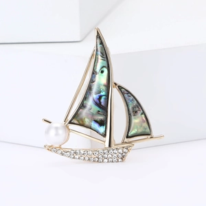 Elegante spilla a forma di barca a vela dorata con vele in madreperla e perla bianca