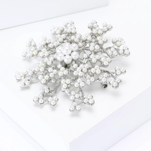 Elegant silver snowflake brooch with pearls on white display stand for women's fashion