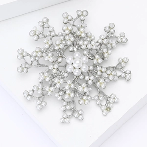 Macro shot of silver snowflake brooch featuring elegant white pearls on a minimalist stand