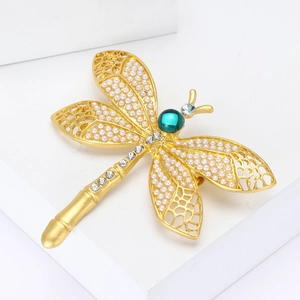 Broche libellule vintage dorée avec perles blanches et pierre verte sur fond blanc épuré