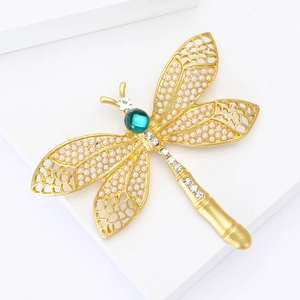 Élégante broche libellule avec perles et gemme verte sur fond géométrique blanc