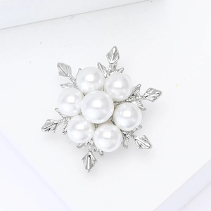 Détail d'une broche flocon de neige argentée avec perles blanches et feuilles ciselées