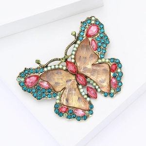 Close-up of alloy butterfly brooch with blue and pink rhinestones on a golden base