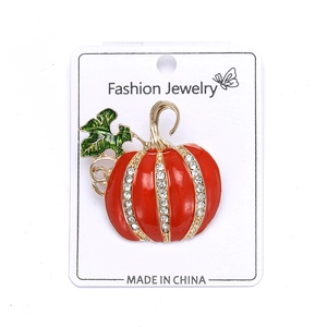 Detail of pumpkin brooch with red enamel and vertical white rhinestone rows on gold alloy