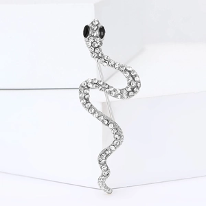 Vue détaillée d'une broche serpent en argent avec strass sur un support géométrique blanc