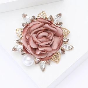 Detailed close-up of a pink fabric rose brooch with crystal leaves and a white pearl