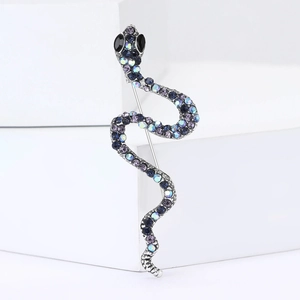 Broche serpent élégante ornée de cristaux bleus et violets sur un piédestal blanc