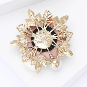 Macro detail of the golden alloy back with a secure pin clasp on a floral fabric brooch