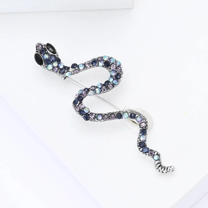 Gros plan détaillé d'une broche serpent avec strass bleus sur un support blanc épuré