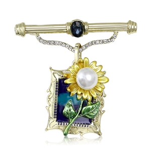 Vintage gold sunflower brooch with blue gemstone and enamel art on white background