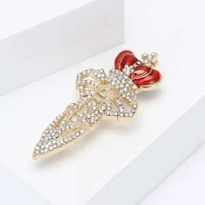 Vintage sword brooch with a red crown and iridescent crystals on a white pedestal