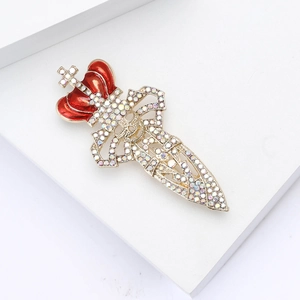 Detail of vintage crown sword brooch with gold finish, red enamel, and sparkling crystals