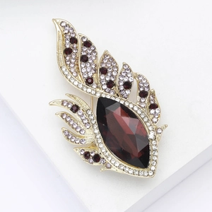 Macro detail of alloy phoenix feather brooch with red rhinestone and gold finish