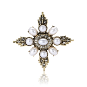 Vintage Baroque starburst brooch with pearls and crystals on a white reflective base