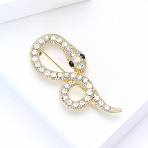 Close-up of gold-plated snake brooch with white rhinestones on minimalist pedestal