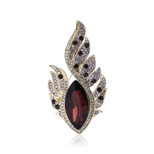 Elegant gold-plated feather brooch with red crystal and purple rhinestones on white background