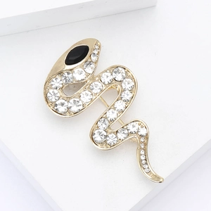 Macro shot of gold snake brooch featuring white crystals and a black gemstone eye