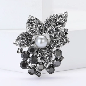 Vue macro d'une broche feuille vintage avec strass noirs et une perle centrale élégante