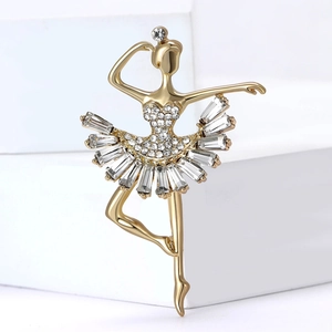Elegant gold ballerina brooch with sparkling crystals on white geometric stand
