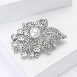 Détail d'une broche feuille en alliage argenté avec perle blanche et strass brillants