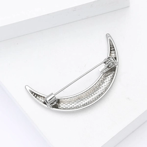 Detailed macro view of silver crescent moon brooch with unique textured inner surface