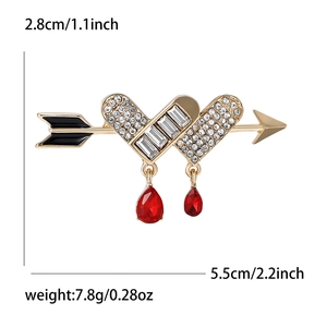 Elegante spilla a cuore e freccia dorata con strass bianchi e pendenti a goccia rossi