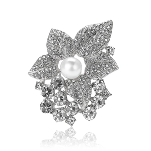 Élégante broche feuille argentée avec perles et strass sur fond blanc réfléchissant