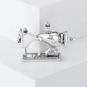 Macro view of vintage silver sewing machine brooch featuring sparkling crystal accents