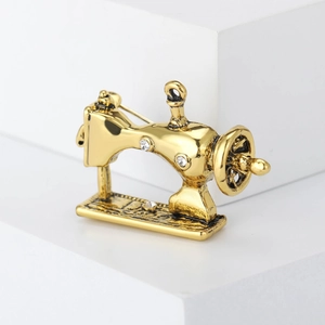 Vintage gold sewing machine brooch with sparkling white rhinestones and retro design