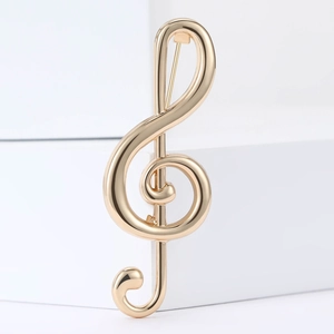 Broche clé de sol dorée polie pour costumes et manteaux sur un socle géométrique