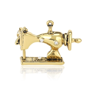 Vintage gold sewing machine brooch with clear rhinestones on a clean white background