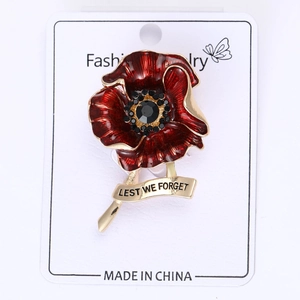 Detail of red enamel poppy brooch with crystals and 'LEST WE FORGET' engraving