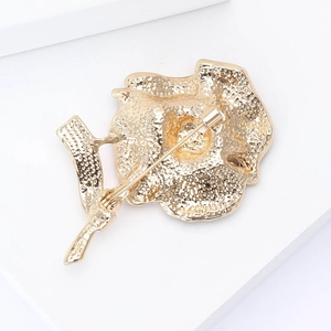 Macro view of the golden metal poppy brooch back featuring the safety pin lock and texture