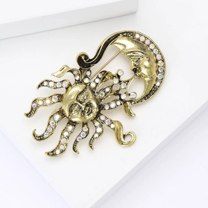 Détail d'une broche vintage soleil et lune dorée sertie de strass irisés brillants