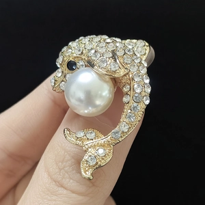 Détail macro d'une broche dauphin avec cristaux étincelants et une grande perle blanche