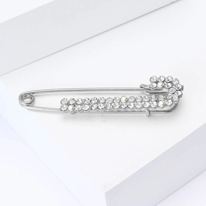 Detailed view of a silver-toned alloy safety pin brooch with sparkling white rhinestones