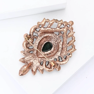 Detailed macro view showing the bronze alloy brooch back with pin clasp and green gemstone