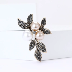 Vintage leaf brooch with pearls and grey rhinestones on minimalist white block display