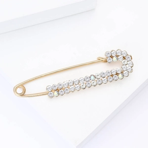 Detailed macro view of a gold safety pin brooch with sparkling rhinestone inlay details